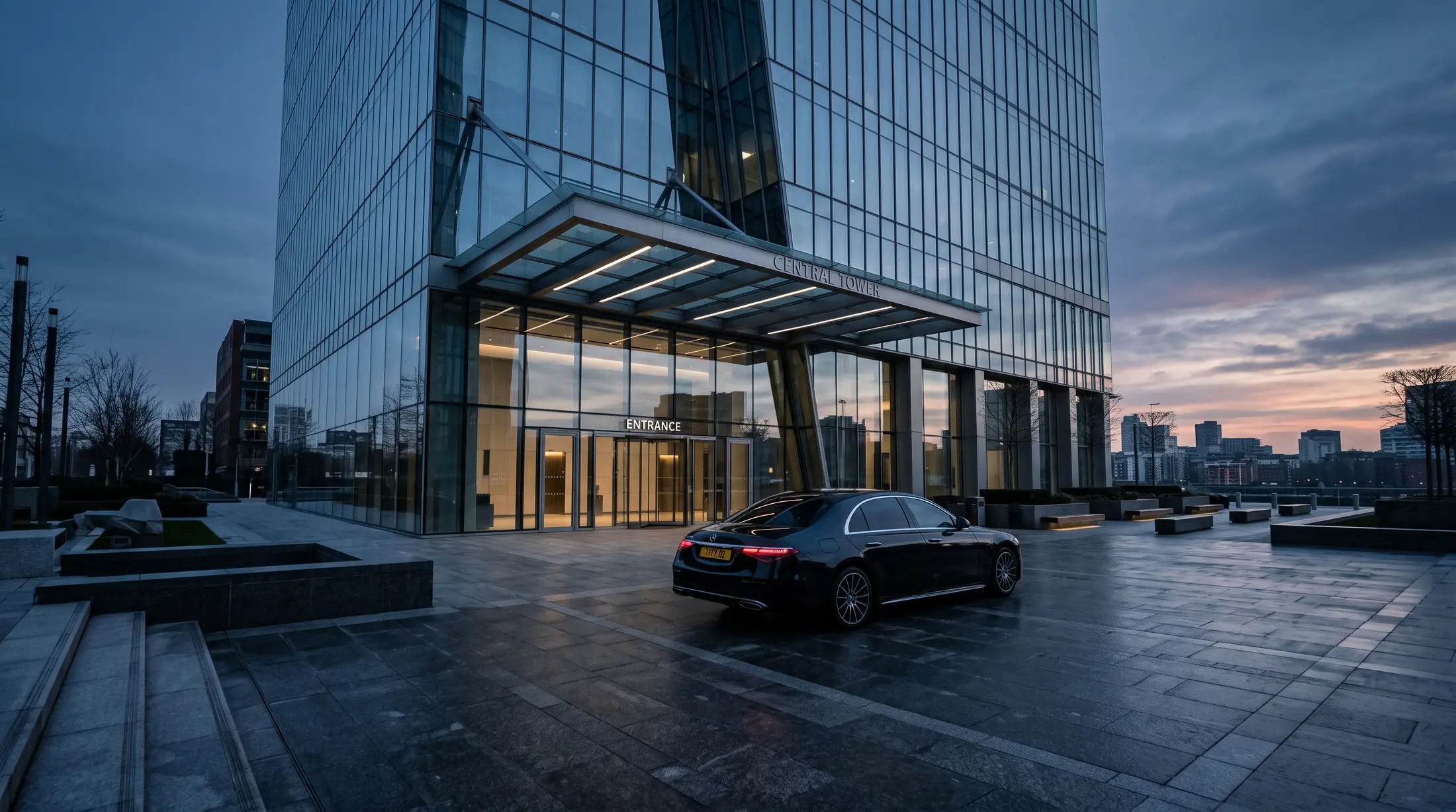A chauffeur car waiting outside an office tower at dawn